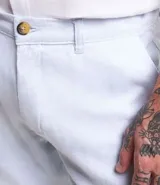 Bermuda de hombre en lino color gris claro, de corte recto, con textura discreta, bolsillos laterales y cierre frontal con botón y cremallera.