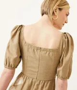 Vestido midi de lino color beige con estampado de follaje blanco, escote corazón con lazo, mangas 3/4 abullonadas y lastex en la espalda.