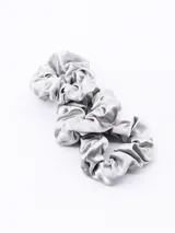 Set de tres scrunchies de tela satinada en color plateado, con diseño fruncido y elástico interno.