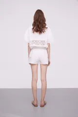 Short blanco de algodón con cintura elástica y detalles de encaje crochet en los laterales y el ruedo.