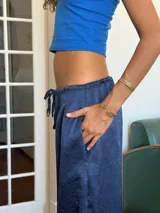 Pantalón de corte holgado y tiro alto, confeccionado en tela satinada color marrón oscuro. Presenta cintura elástica con cordón ajustable y diseño amplio en las piernas.
