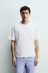 Set de pijama para hombre compuesto por una remera blanca de cuello redondo y mangas cortas, y un pantalón celeste a rayas verticales con cintura elástica y bolsillos laterales.