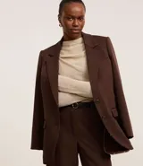 Blusa de punto leve color beige, con cuello degagê, mangas largas y fruncido lateral.