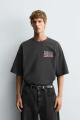 Camiseta negra con efecto lavado, corte boxy fit, cuello redondo y manga corta. Presenta un estampado frontal con texto en tonos turquesa, rojo y blanco que dice "Tuesday 600 Marathon Day Hyde Park".