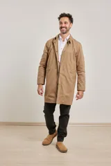 Gabardina color beige de algodón, con cuello clásico, cierre frontal con botones, dos bolsillos de ribete delanteros, bolsillo interior con botón y abertura posterior en el bajo.