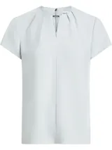 Blusa celeste de poliéster reciclado con cuello redondo, mangas cortas y cierre con cremallera en la espalda. Presenta una abertura en la parte delantera con una barra metálica decorativa.