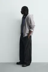 Pantalón wide fit de algodón con efecto lavado, corte recto y holgado. Presenta un cierre frontal cruzado con botones y un alamar metálico distintivo, además de bolsillos frontales y traseros de plastrón.