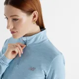 Buzo celeste jaspeado de New Balance, con cierre de cremallera corto, mangas largas con orificios para los pulgares y logo reflectivo en el pecho.