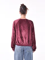 Campera negra de terciopelo con cierre frontal y apliques de lentejuelas plateadas formando líneas verticales.