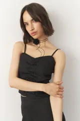 Top negro sin mangas de tela satinada y texturizada, con costuras que generan frunces.