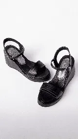 Sandalias negras de cuero con plataforma y cuña baja. Tiras anchas sobre el empeine y tobillera con hebilla metálica.