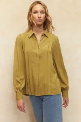 Camisa blanca de mangas abullonadas con sutiles plisados frontales, cuello clásico y corte relajado.