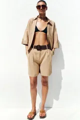 Bermuda de tiro alto color azul marino, con pinzas delanteras, bolsillos laterales y cinturón trenzado color marrón.