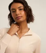 Campera deportiva de microfibra color beige con cuello alto y cierre frontal de cremallera.