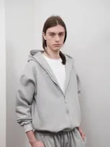 Campera con capucha y cierre frontal metálico, confeccionada en felpa de algodón. Presenta un diseño oversize con bolsillos laterales y puños elásticos.