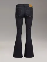 Pantalón de jean azul oscuro, de corte ajustado en la cadera y muslos, y acampanado a partir de la rodilla.