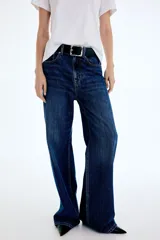 Pantalón jean de denim azul, tiro alto, con diseño wide leg de cinco bolsillos y cierre frontal con botón y cremallera.
