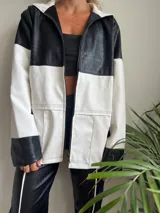 Campera con capucha, de cuero sintético, con diseño color block en blanco y negro y cierre frontal.