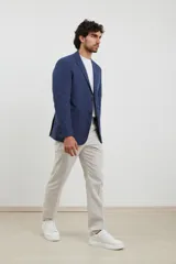 Saco azul de lino, de corte clásico, con solapa de muesca, cierre de dos botones, bolsillos frontales con solapa y aberturas traseras.