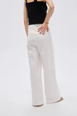 Pantalón blanco de tiro alto, corte ancho y recto, confeccionado en algodón con elastano, con pinzas y cierre frontal con botón.