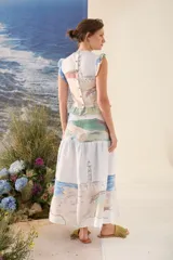 Falda larga de corte evasé, confeccionada en tela liviana de base blanca con un estampado artístico de paisajes en tonos celestes, verdes y rosados.
