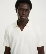 Remera polo de manga corta con cuello tradicional sin botones, confeccionada en tejido con textura mini grid.