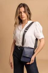Bandolera pequeña tipo phonebag de cuero sintético color azul, con solapa frontal, cierre magnético y correa de cinta regulable con logo de la marca.