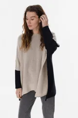 Poncho de tejido de punto con diseño oversize y aberturas laterales. Presenta un acabado con destellos brillantes y cuello redondo amplio.