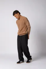 Sweater de punto grueso con textura waffle, de calce relajado y cuello redondo. Presenta puños y ruedo acanalados, con un pequeño parche con logo en el puño izquierdo.