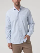 Camisa de manga larga de algodón celeste con sutil patrón a cuadros, cuello camisero, cierre frontal con botones y un bolsillo en el pecho con logo bordado.