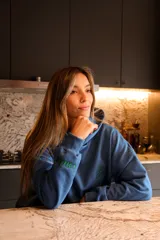 Canguro azul con capucha y logo de flor bordado en verde.