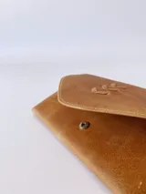 Billetera de cuero color camel con sistema de cierre con broche y monedero externo.