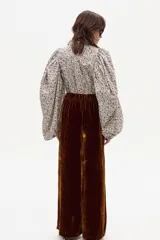 Camisa de manga larga con estampado floral en tonos crema, marrón, rosa y azul. Presenta cuello clásico y un corte que parece ser ajustado o con volumen en las mangas.