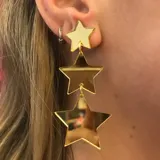 Aros colgantes dorados con tres estrellas espejadas de diferentes tamaños unidas por argollas.