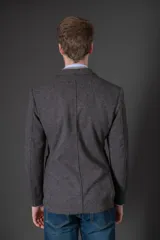 Saco de lana gris oscuro con textura, corte entallado y bolsillos laterales. Incluye un chaleco interior acolchado desmontable en color gris claro con cierre frontal.