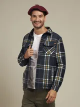 Sobrecamisa a cuadros azul, verde y blanco, con cuello camisero, cierre frontal con botones, dos bolsillos de parche con botón en el pecho y puños abotonados.