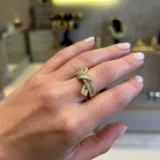 Anillo dorado con diseño de nudo, hecho de acero y zirconia.