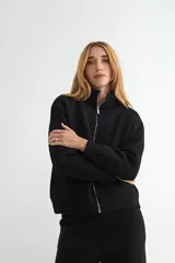 Abrigo de punto negro con cuello alto y cierre frontal completo. Presenta un diseño de corte recto con bolsillos frontales y terminaciones en tejido acanalado.