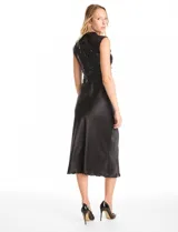 Vestido midi de satén color champagne con corte al bies y escote recto, acompañado por un top sin mangas de cuello alto cubierto de lentejuelas doradas con detalle drapeado en la cintura.
