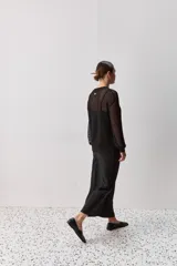 Falda midi color negro al bies, confeccionada en tela de textura suave y caída fluida, de diseño minimalista y silueta recta.