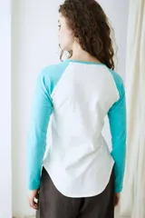 Remera de manga larga estilo raglan, color verde militar, con cuello redondo y dobladillo inferior curvado.