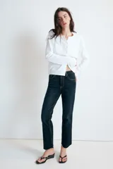 Jeans de tiro alto con cinco bolsillos, diseño cropped flare y bajo sin costuras. Cuenta con cierre frontal de cremallera y botón metálico.