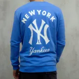 Buzo deportivo azul con cuello redondo, puños y cintura acanalados. Estampado frontal con el logo de los New York Yankees y la inscripción "New York" en color blanco.