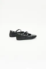 Balerinas negras de cuero con tira sobre el empeine y remaches de níquel de distintos tamaños.