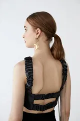 Top corto de cuero sintético negro con breteles fruncidos con elástico y volado central. Espalda unida por tiras elastizadas y fruncidas.