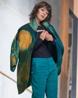Tapado de lana merino afieltrada con teñido artesanal tie dye en tonos verdes y ocres. Tiene cuello alto, cierre cruzado asimétrico con broches, bolsillos laterales y corte holgado.