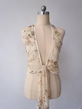 Top halter de color beige con diseño cruzado al frente, escote pronunciado y detalles de bordado con lentejuelas y cuentas doradas.