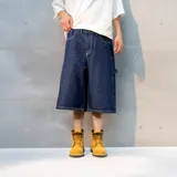 Bermuda de jean estilo baggy, confeccionada en denim de algodón premium con textura rústica. Presenta un diseño de corte amplio, costuras reforzadas en contraste y un bordado distintivo en la parte inferior de la pierna.