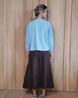 Pollera larga de denim en color gris, con corte acampanado, costuras verticales decorativas y cierre posterior.