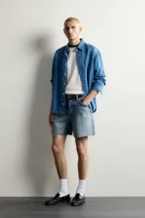 Shorts de denim de algodón con ajuste regular, diseño de cinco bolsillos y efecto lavado. Presenta cierre frontal con cremallera y botón, con el bajo acabado en corte irregular.